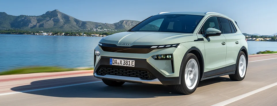 Skoda Elroq in pastellgrün vor einem See in seitlicher Frontansicht