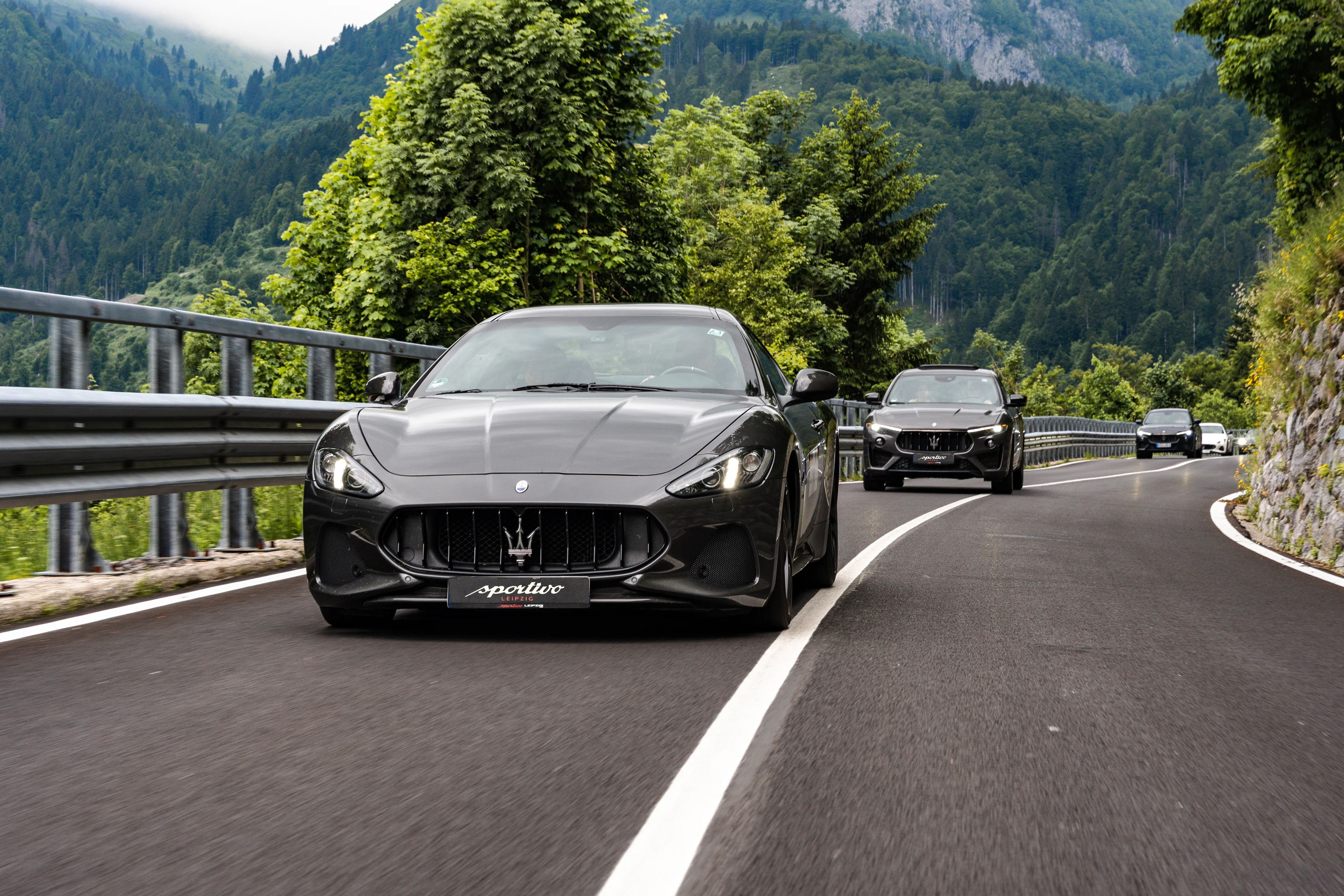 Ein Maserati in dunkelgrau von vorne fotografiert fahr auf einer Landstraße in den Dolomiten