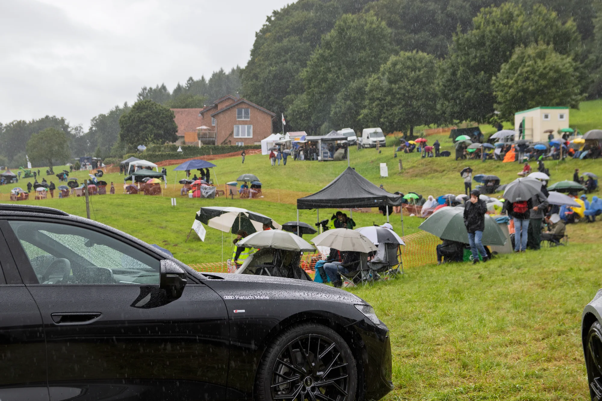 Fahrzeuge und Besucher des 57. Bergrennen auf einer Wiese an der Stecke - Geländeüberblick