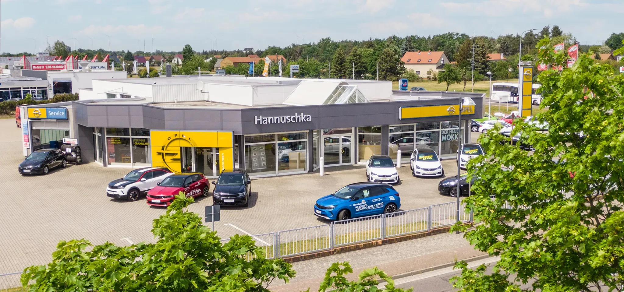 Autohaus Hannuschka, aus der Luft fotografiert, mit blauem Himmel und Fahrzeugen vor dem Autohaus