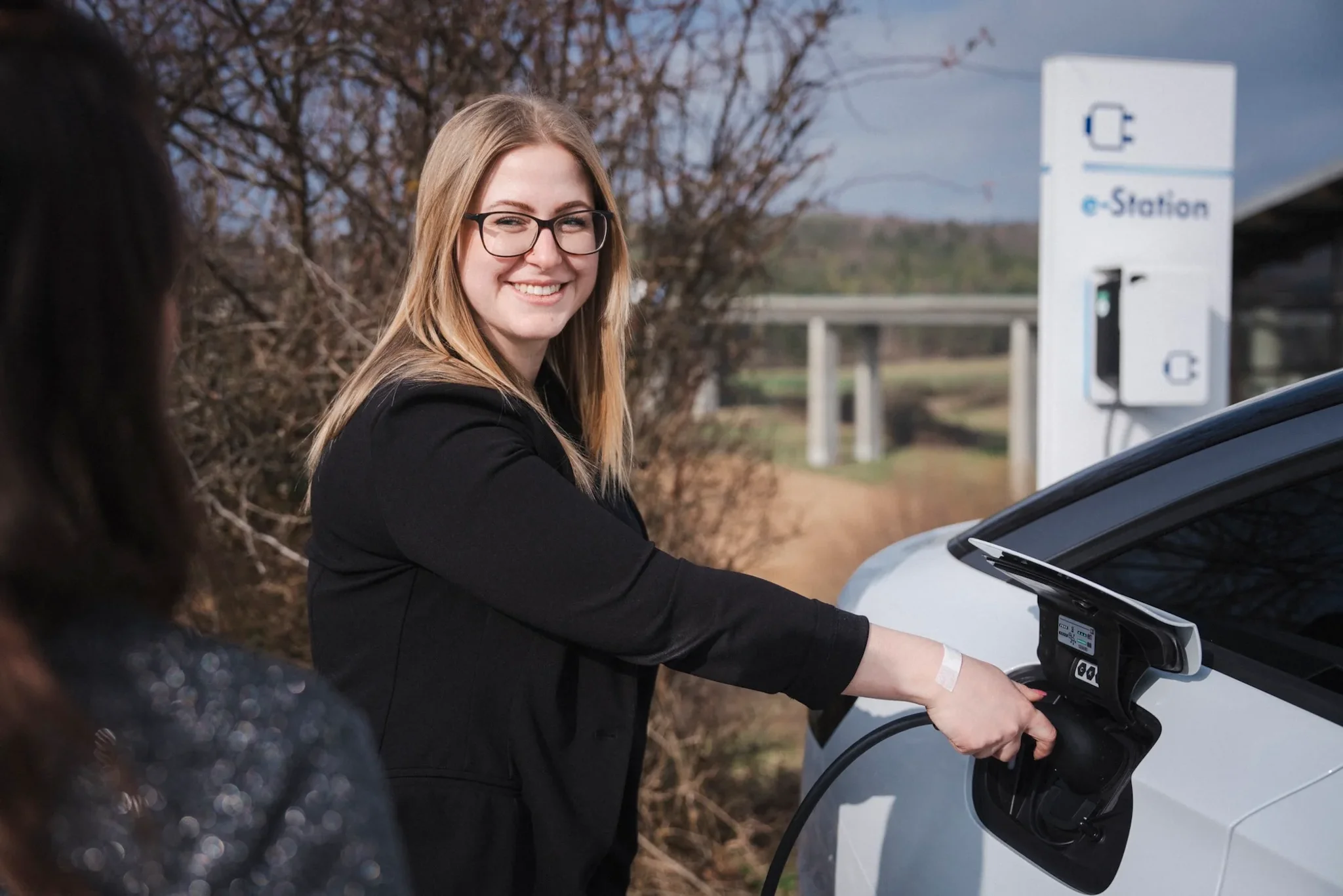 Fahrerin eines Elektrofahrzeug an der Ladesäule beim einstecken des Ladesteckers