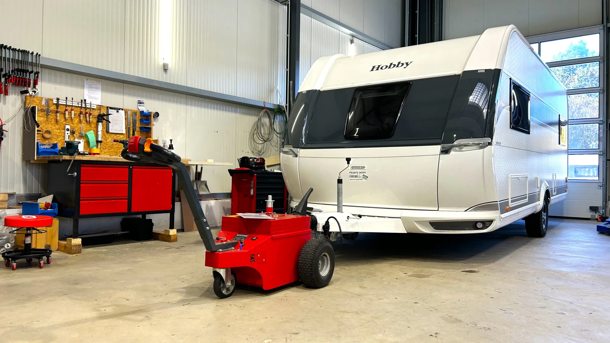 Wohnwagen an einer roten Rangierhilfe in einer Werkstatt