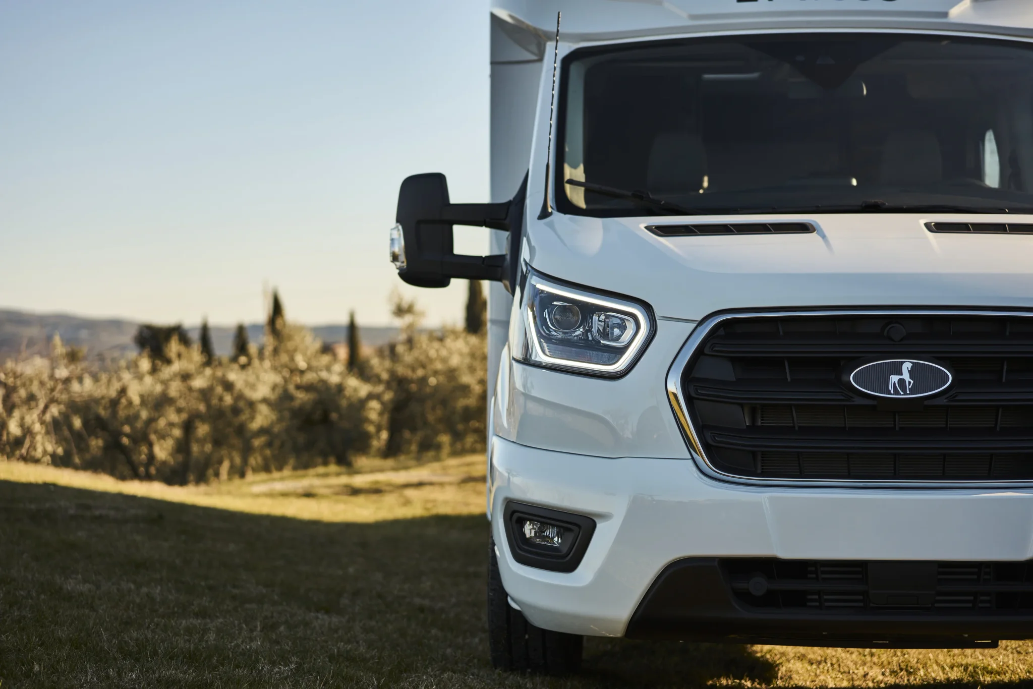 Front eines Ford Etrusco teilintegrierten Wohnmobils mit Bäumen im Hintergrund