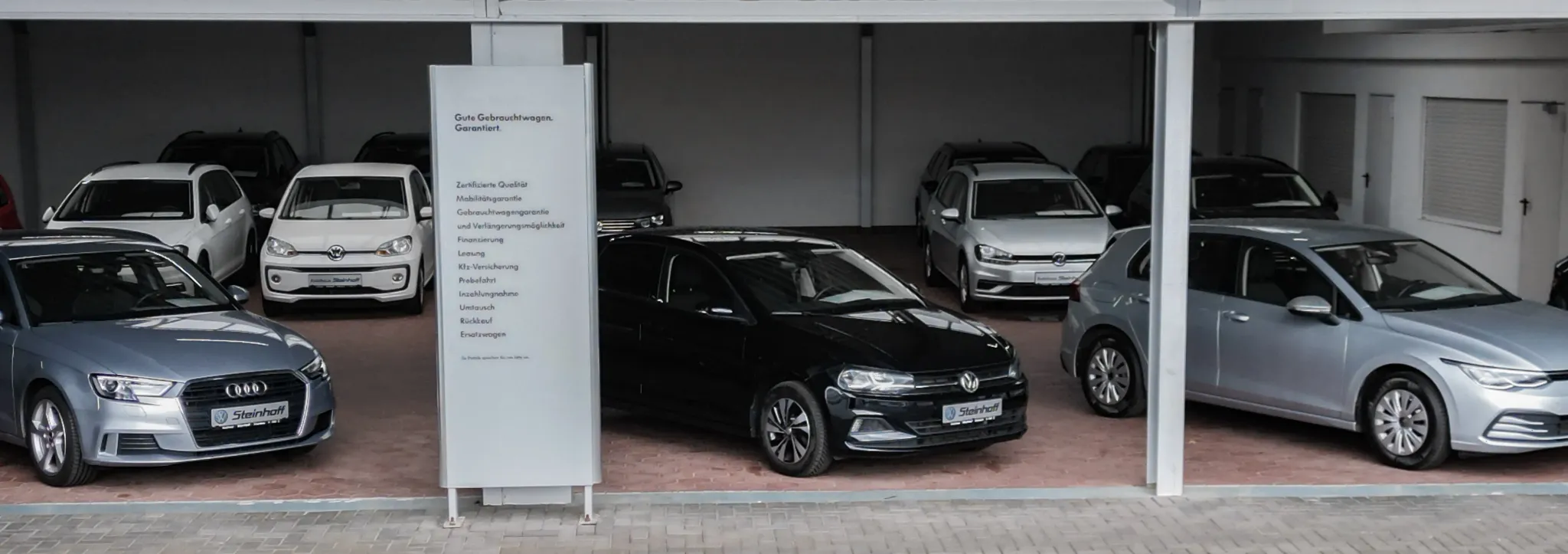 Fahrzeuge verschiedener Marken auf einer überdachten Ausstellungsfläsche