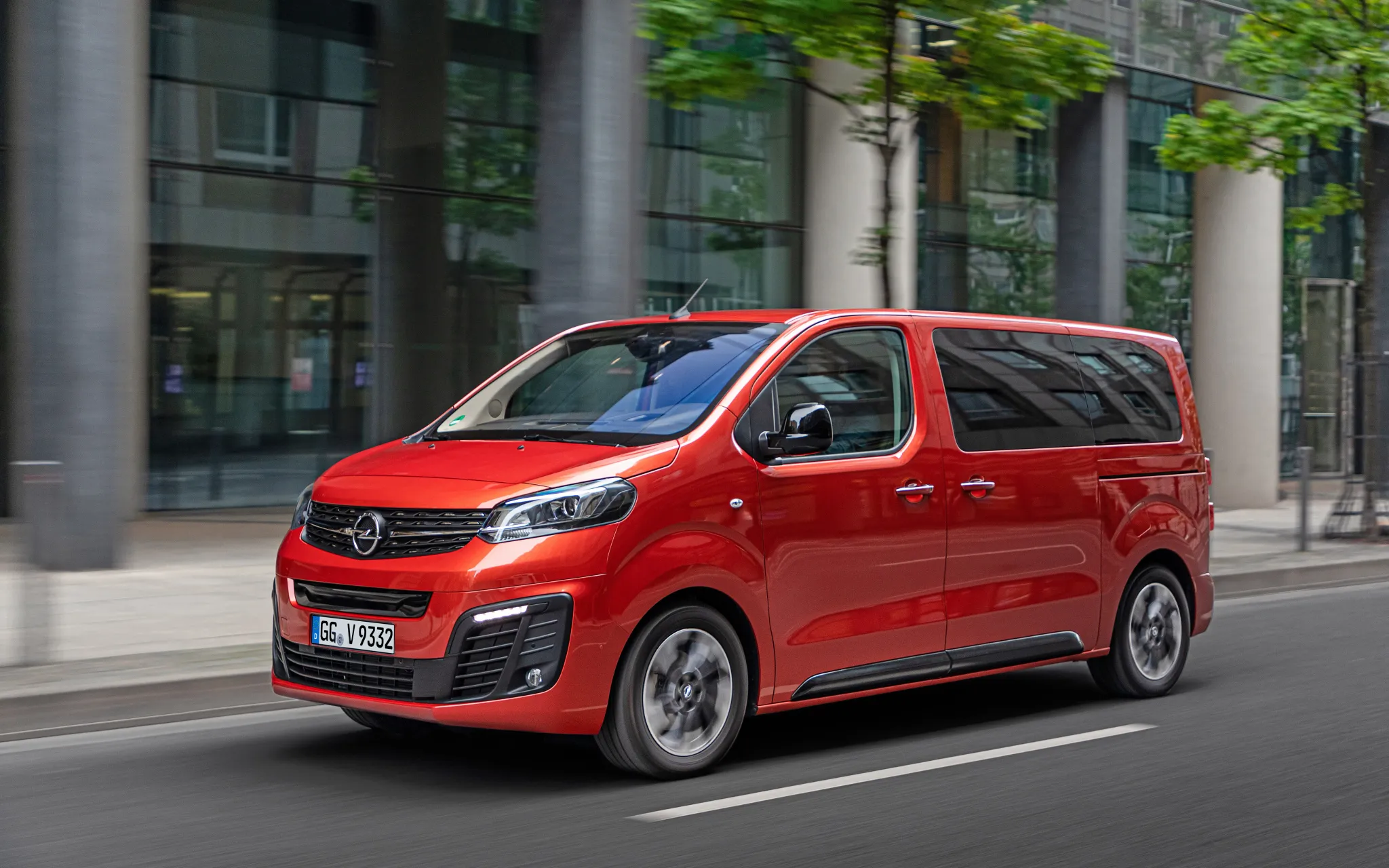 Opel Vivario in Rot fahrend, vor einer Skyline von vorn links fotografiert