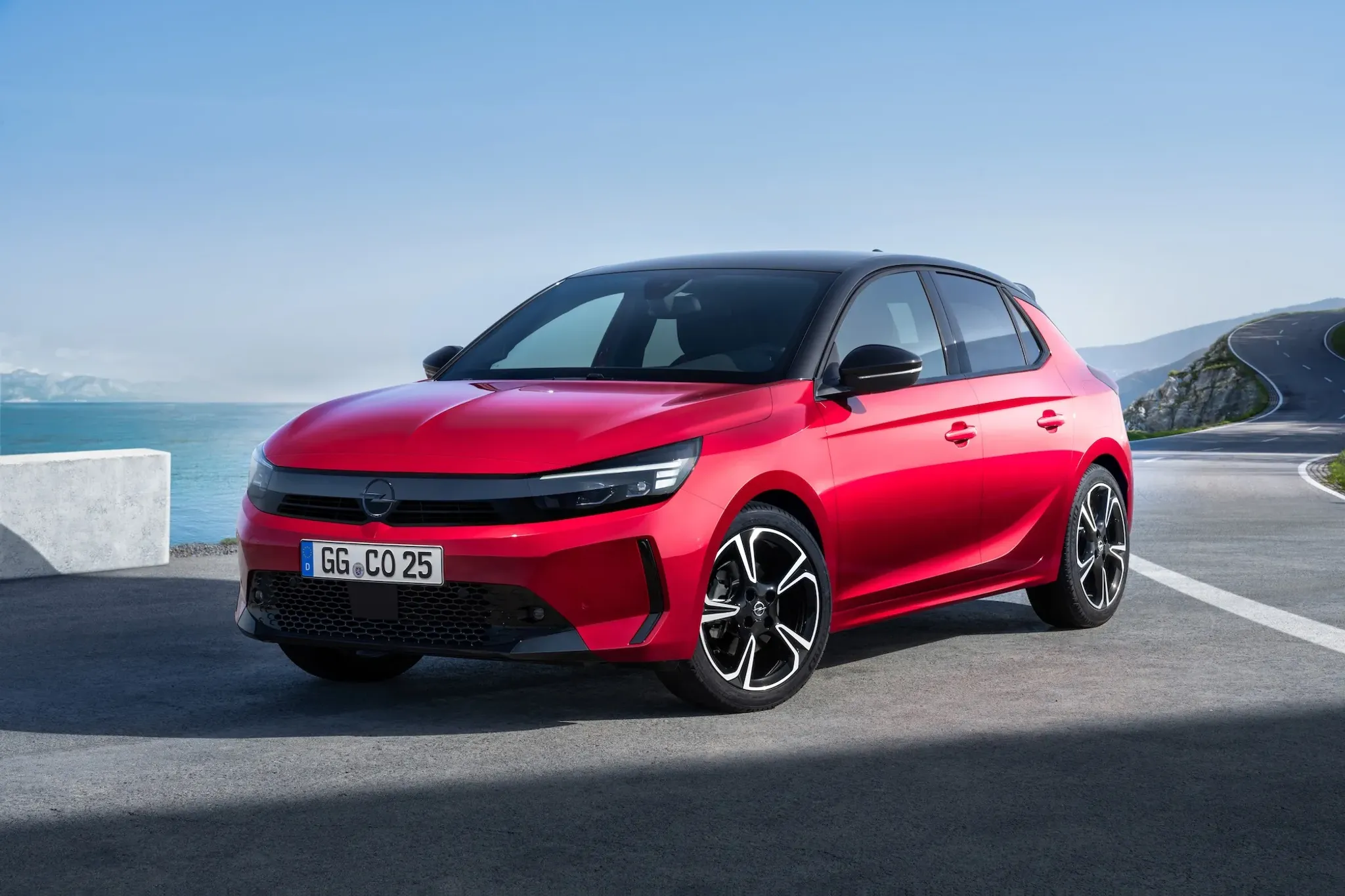 Opel Corsa, rot von Form, links fotografiert auf Asphalt und blauem Himmel
