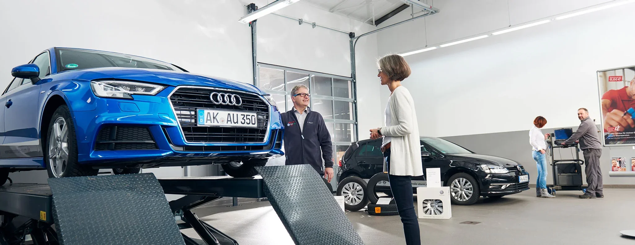 Serviceberater mit Kundinnen bei der Annahme ihres blauen Audi