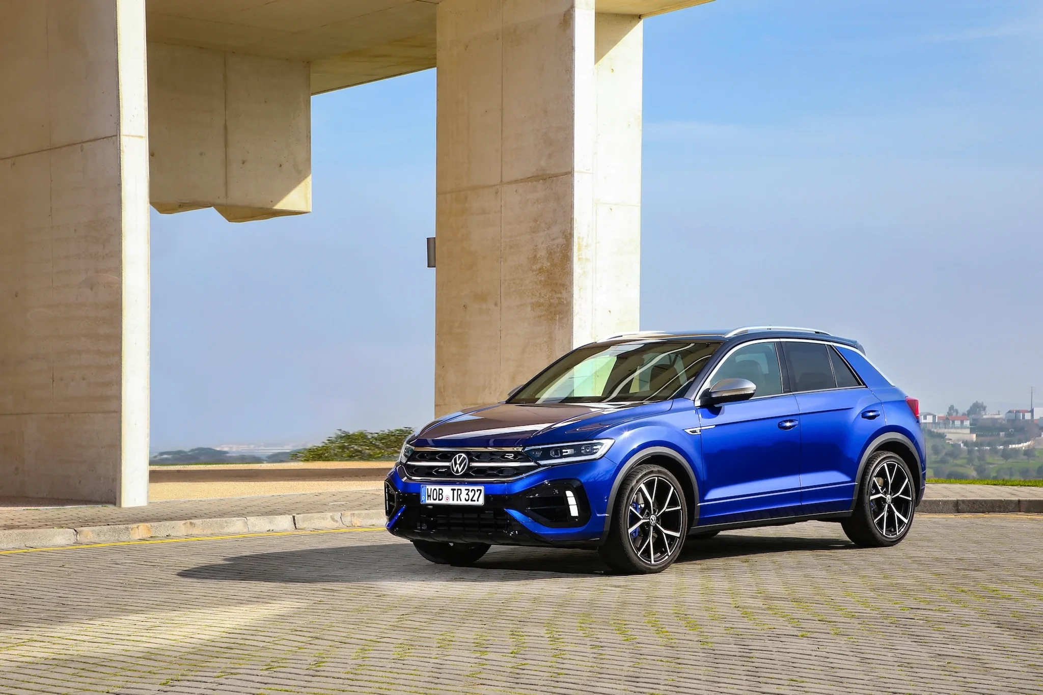 VW T-Roc in blau von der linken Seite fotografiert, vor allem Gebäude