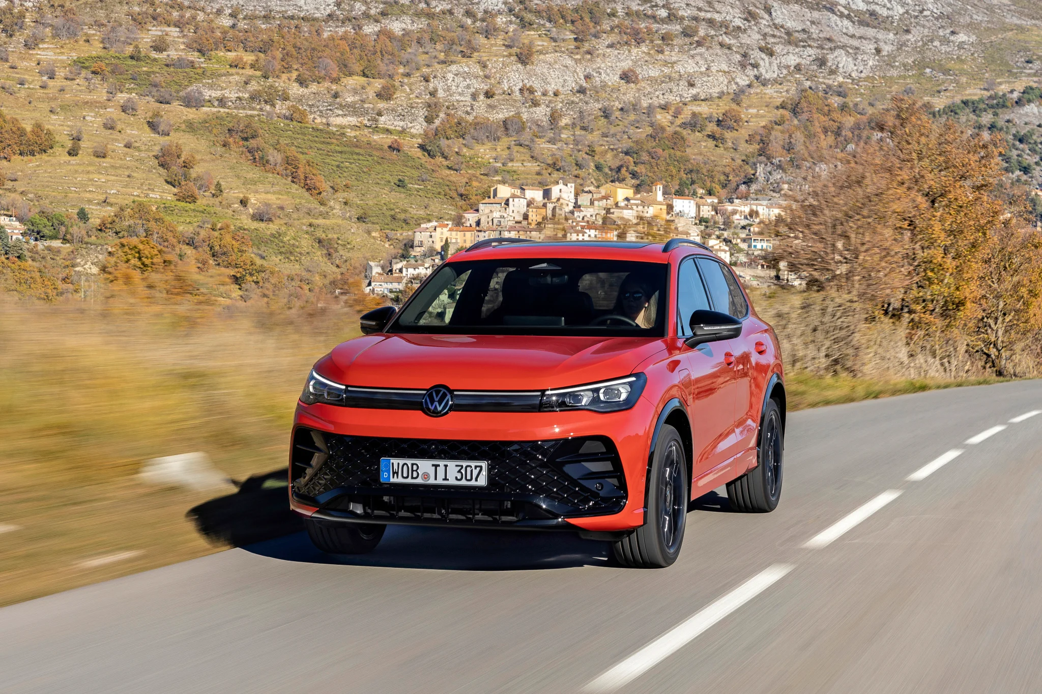 VW Tiguan in Rot fahrend auf einer Landstraße von vorn fotografiert