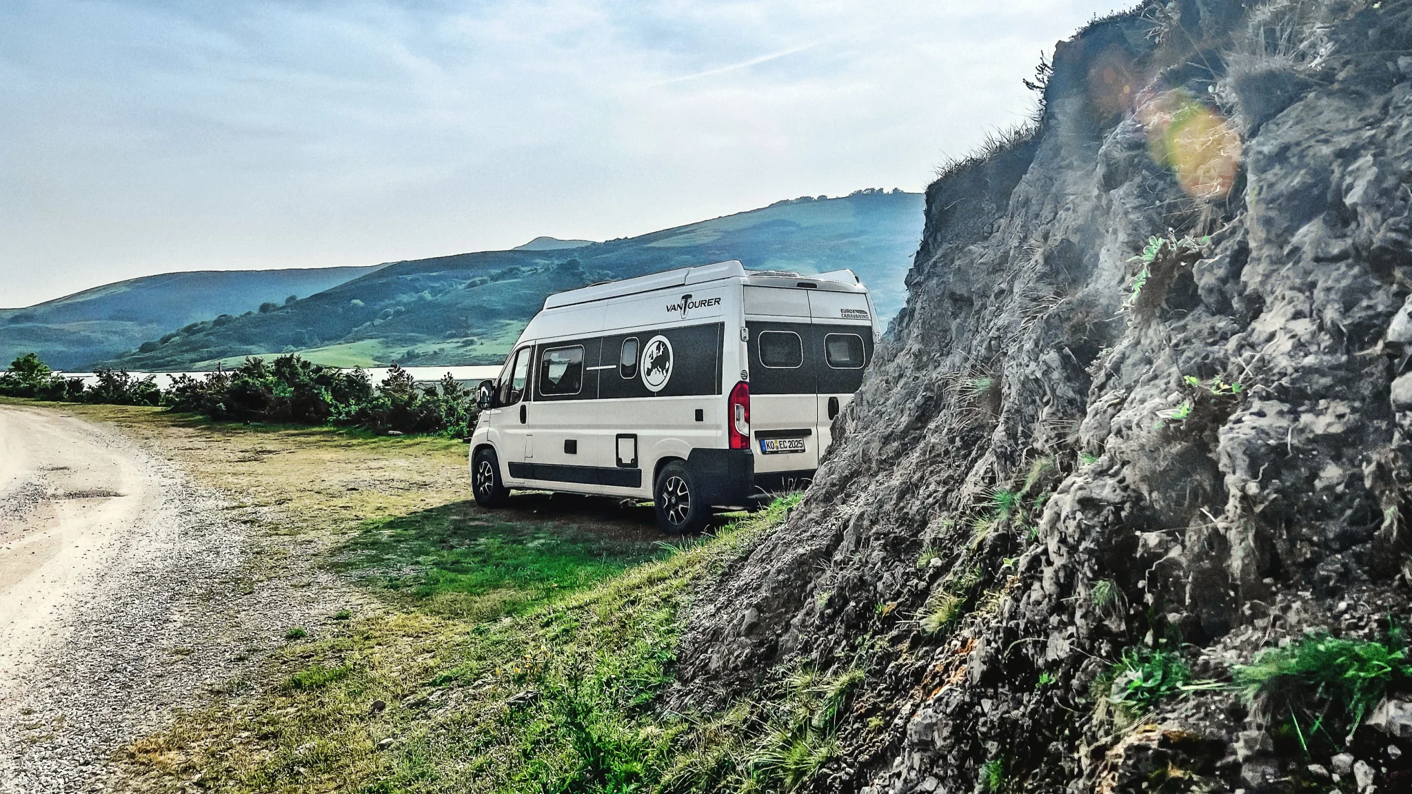 VanTourer Camping Kastenwagen am Straßenrand mit Bergen im Hintergrund