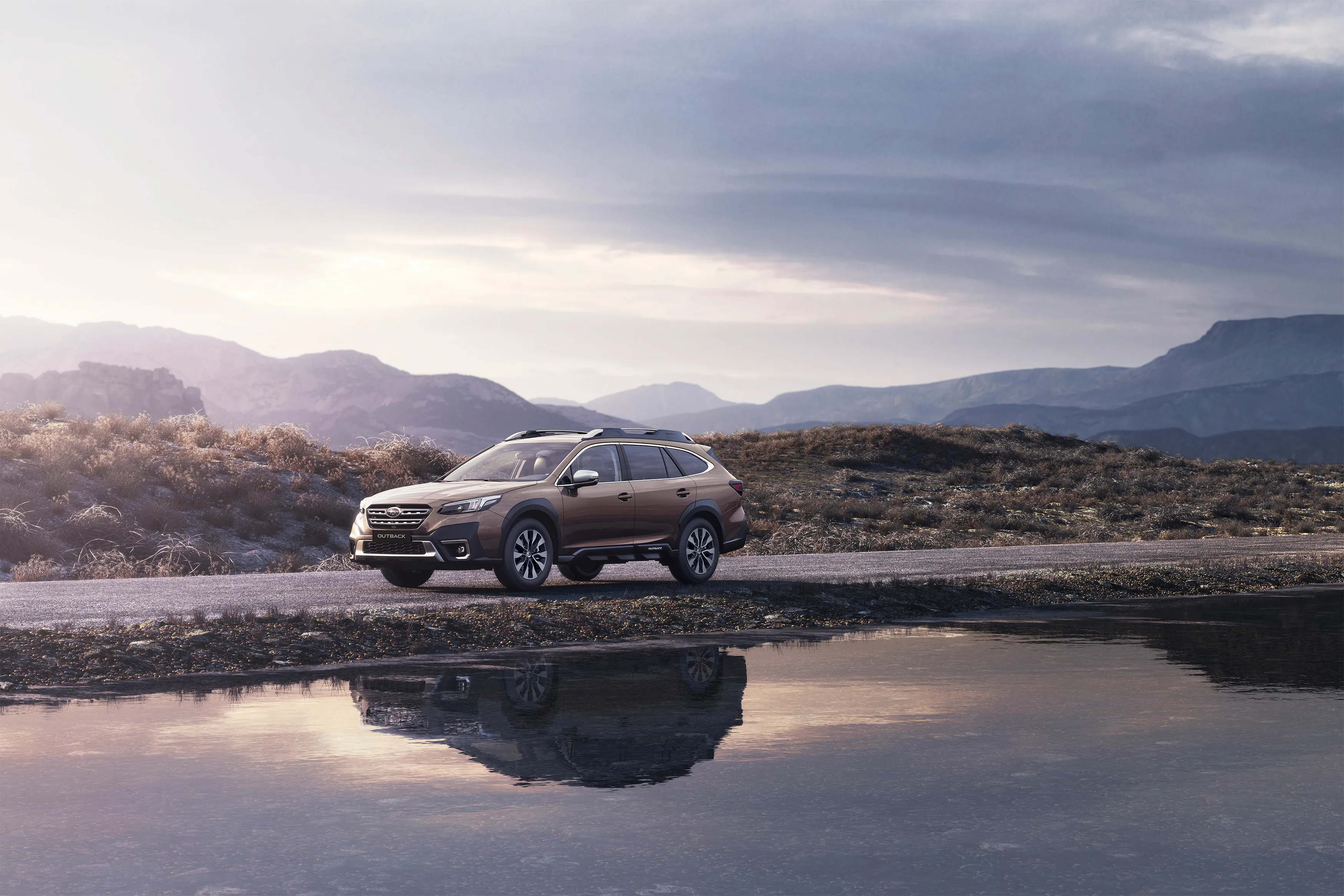 Brauner Subaru Outback auf Straße in bergiger Landschaft, spiegelt sich im Wasser.