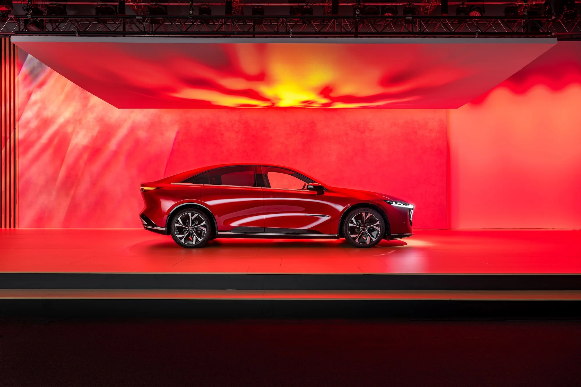 Mazda 6E in Roth Aufnahme von der Seite auf einer Bühne mit Beleuchtung von oben