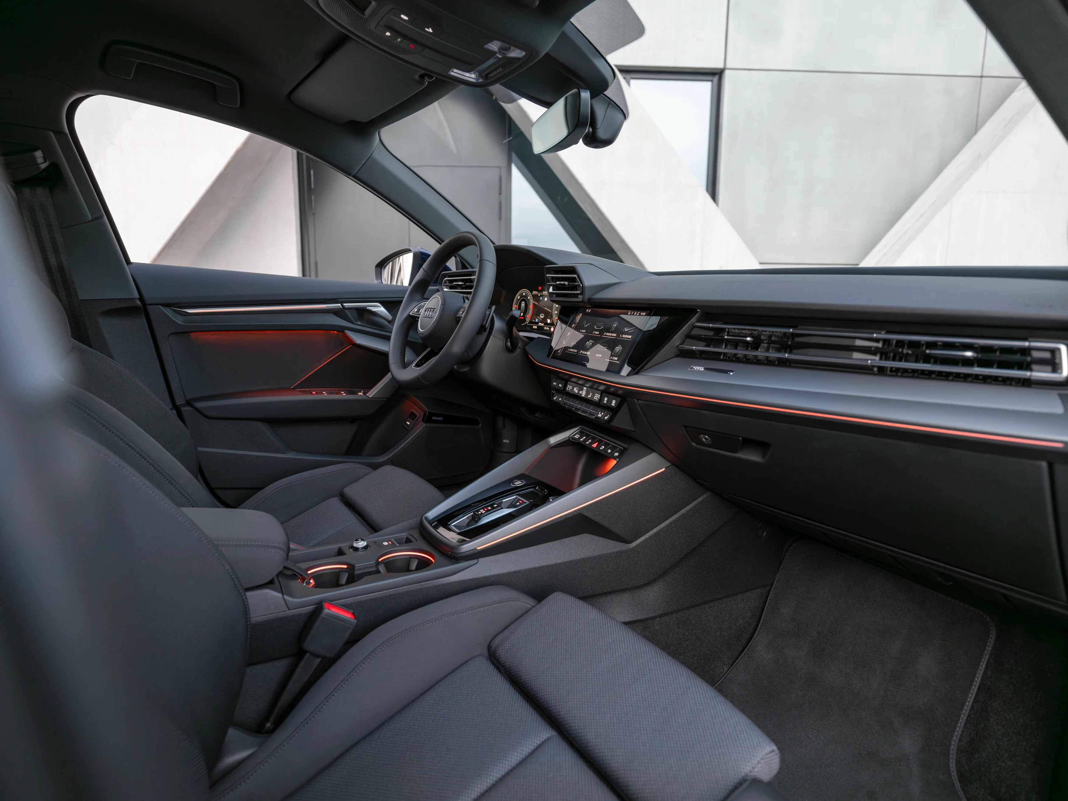 Sicht auf Sitze und Infotainment des Audi A3 Sportback in Schwarz mit orangefarbenen Lichtelementen