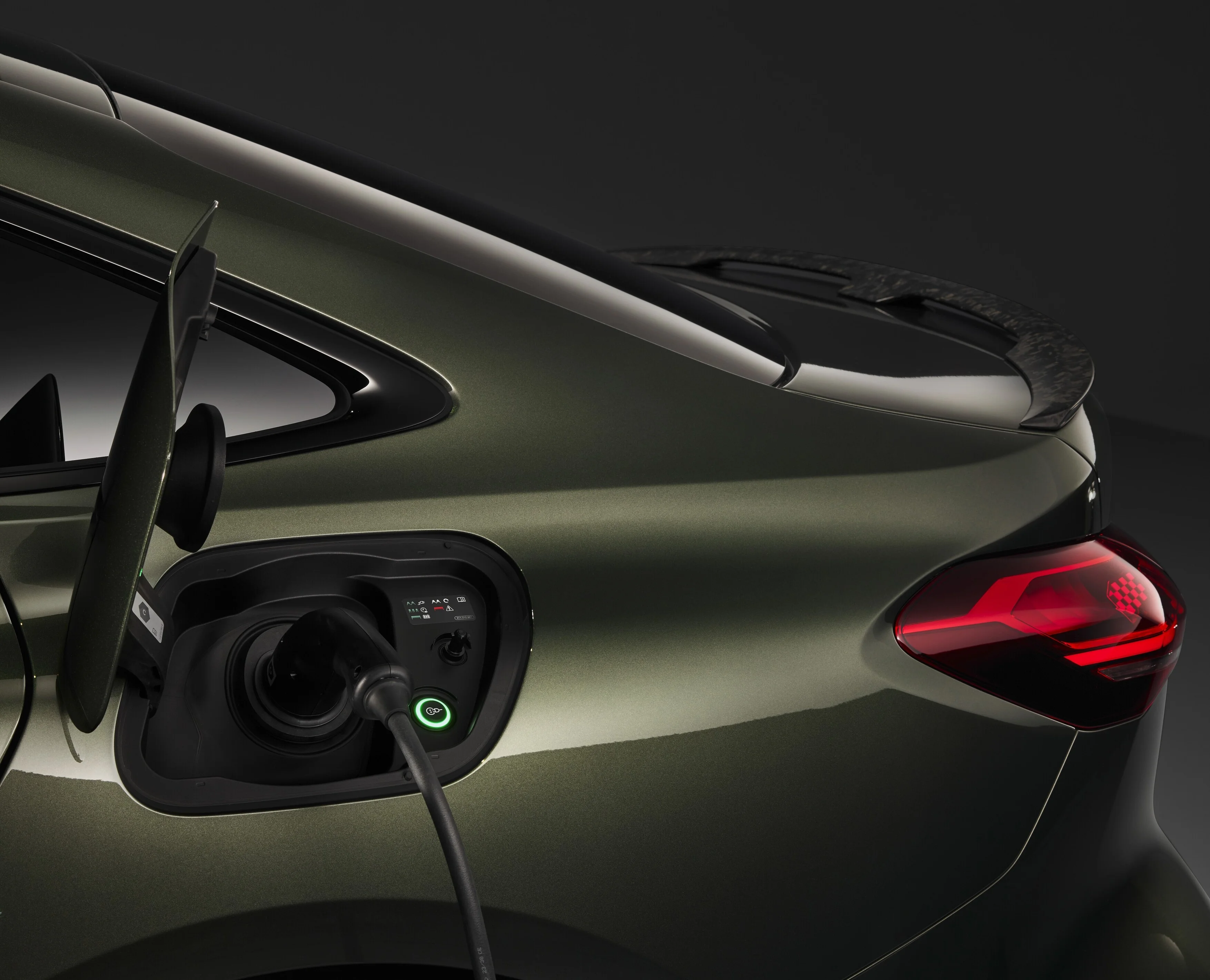 Bildausschnitt der Audi RS 5 Limousine in Grün mit Sicht auf den geöffneten Ladeanschluss mit dunklem Hintergrund.