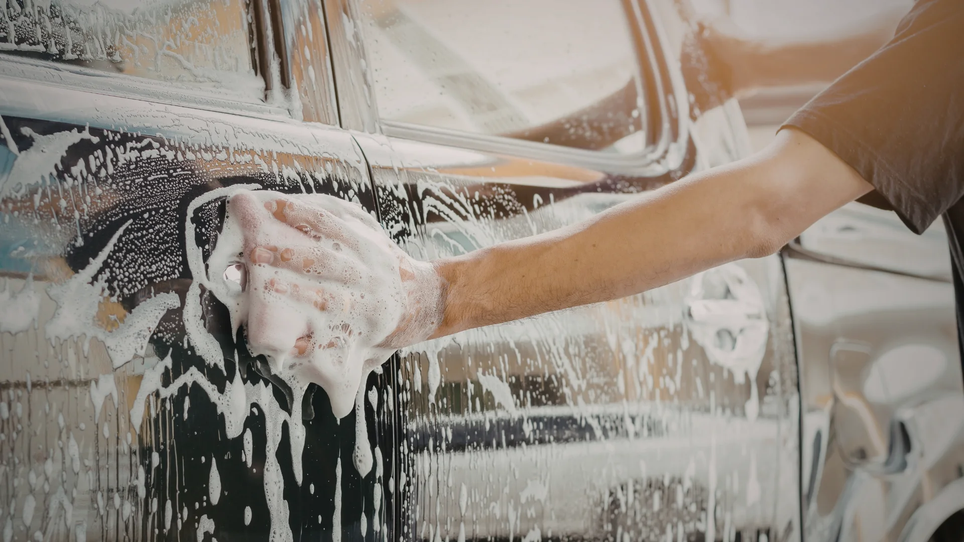 Schwarzes Auto wird mit der Hand gereinigt