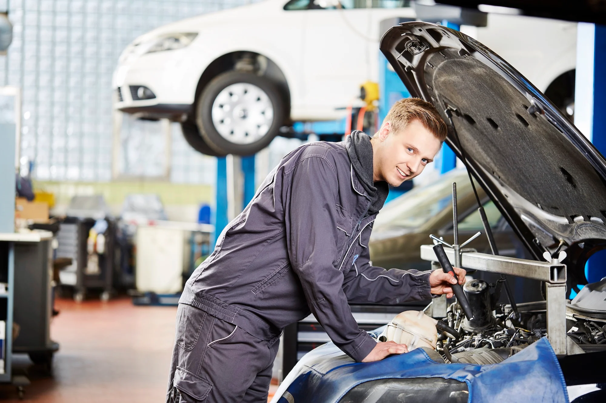 Kfz-Mechaniker im Autohaus Meyer vor einem Auto stehend mit geöffneter Motorhaube