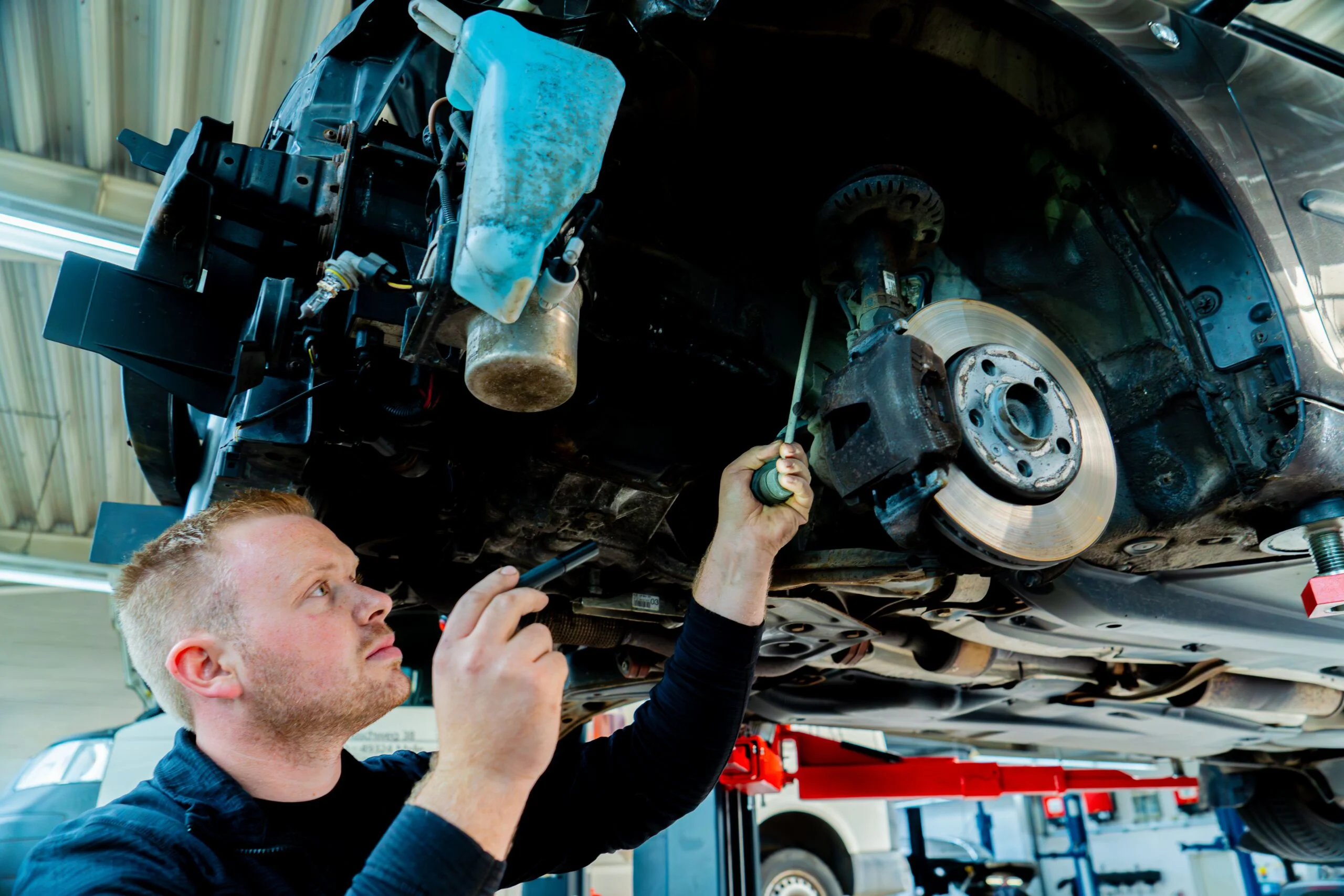 Mitarbeiter des Autohaus Pietsch beim Arbeiten an einem Fahrzeug im Bereich der Vorderachse