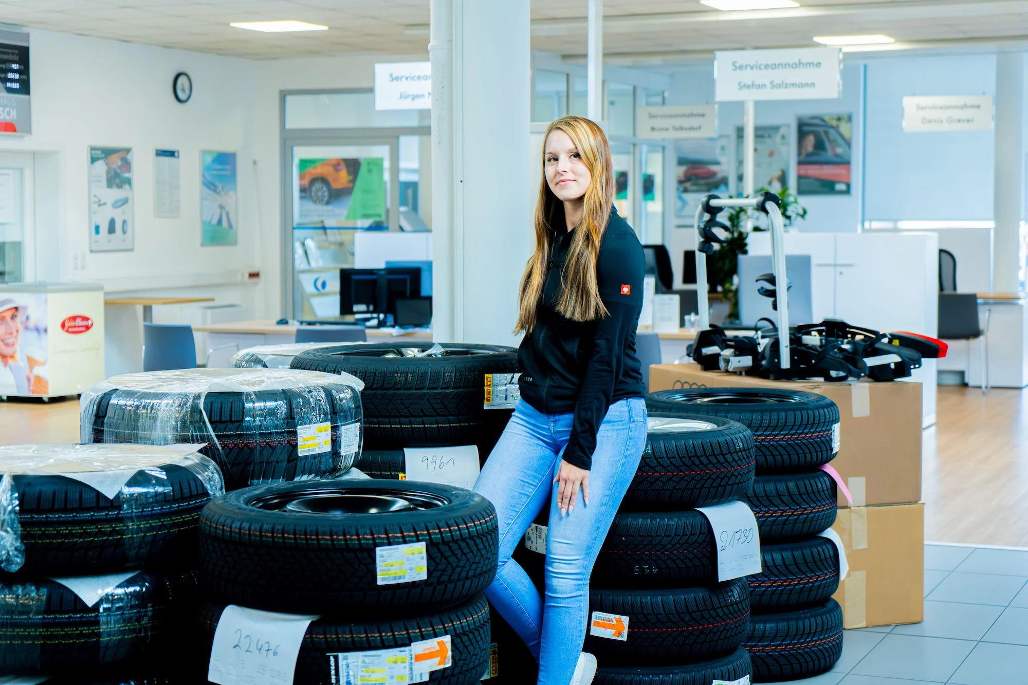 Mitarbeiterin des Autohaus Pietsch sitzend auf einem Reifenstapel