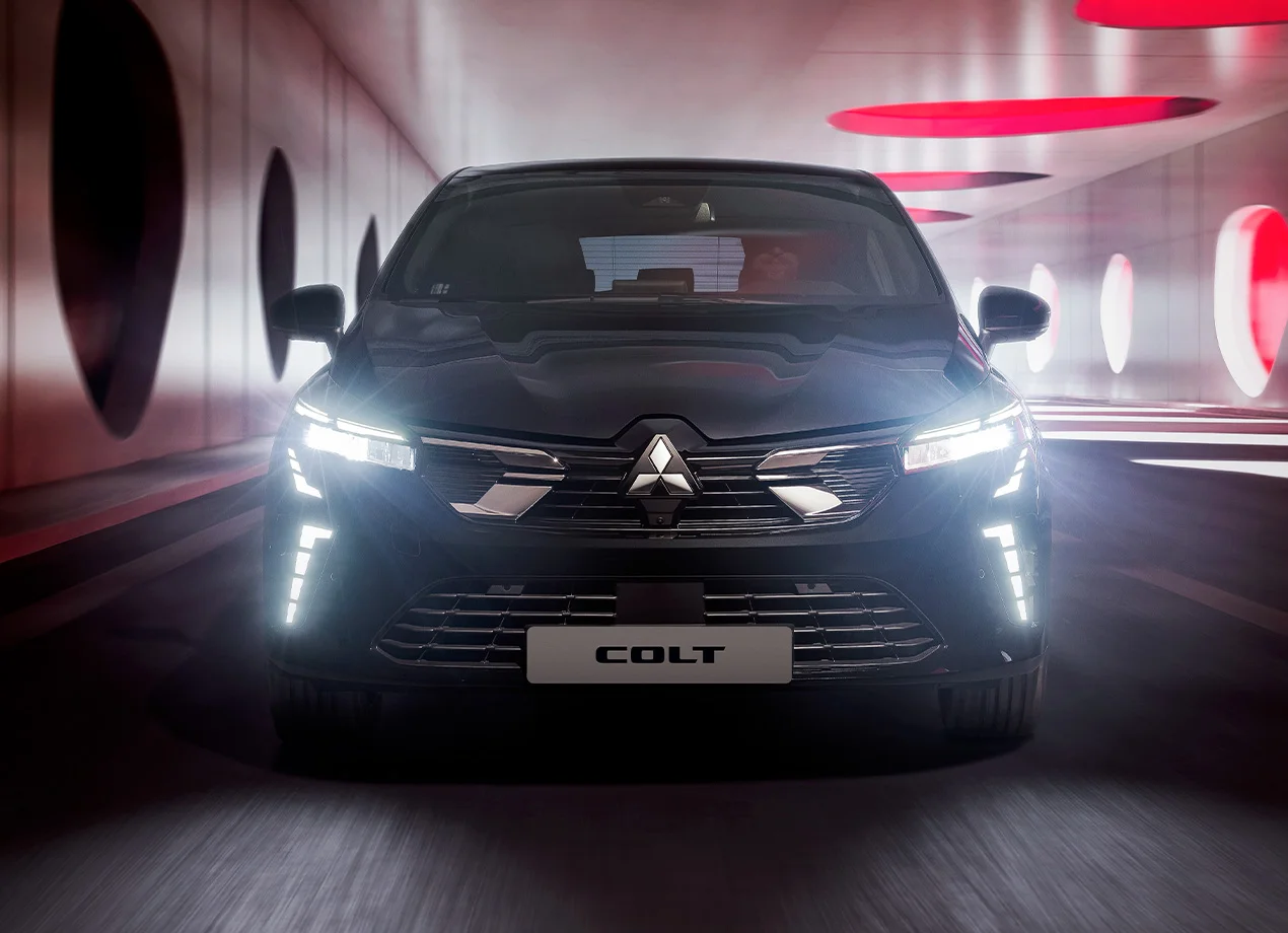 Mitsubishi Colt in grau, mit eingeschalteten LED Scheinwerfern von vorne aufgenommen