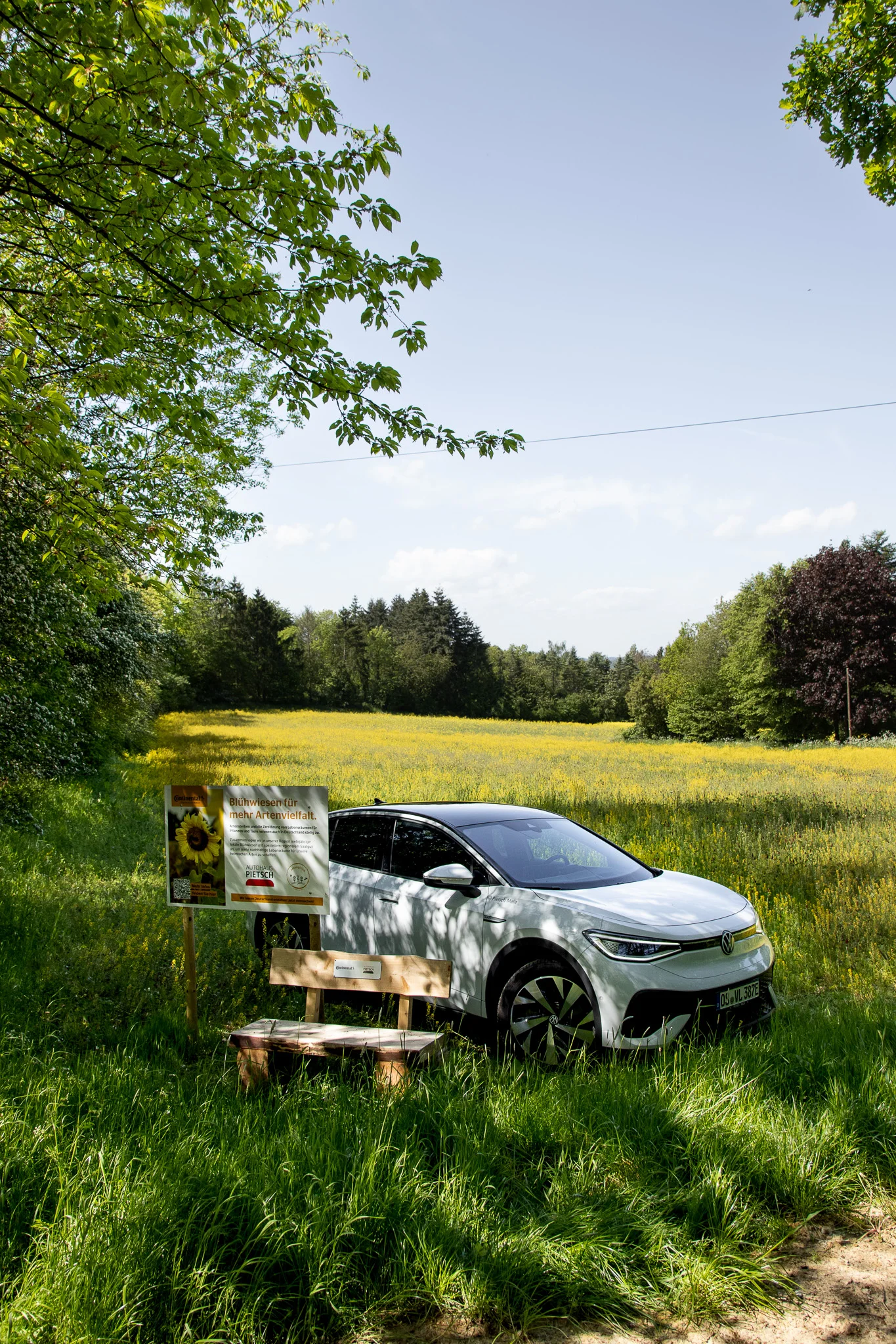 VW ID.4 in Weiss aufgenommen von rechts, stehend vor einem Feld mit gelben Blumen