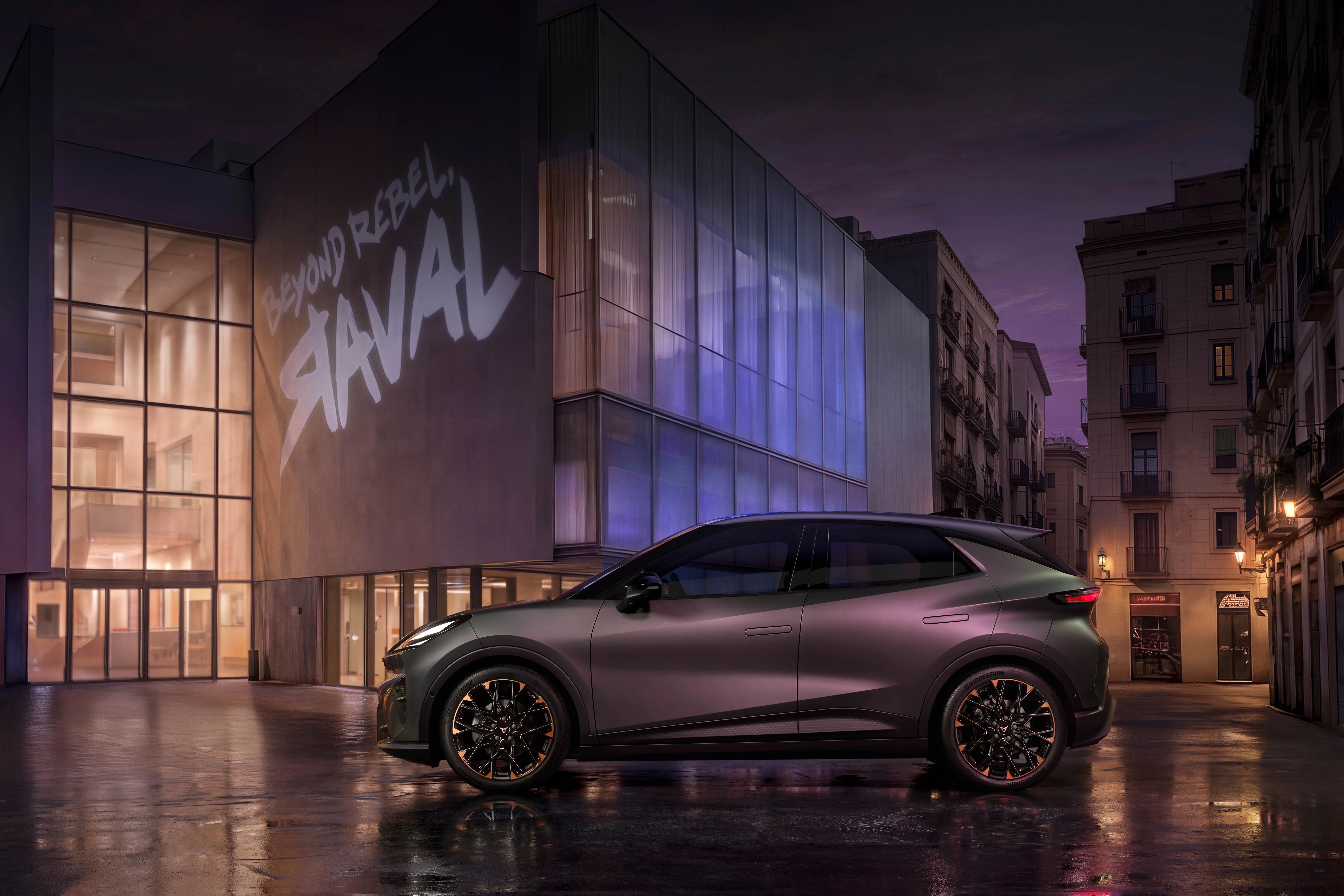 CUPRA Raval in Seitenansicht vor moderner urbaner Architektur bei Abenddämmerung – vollelektrischer Kleinwagen mit markantem Design.