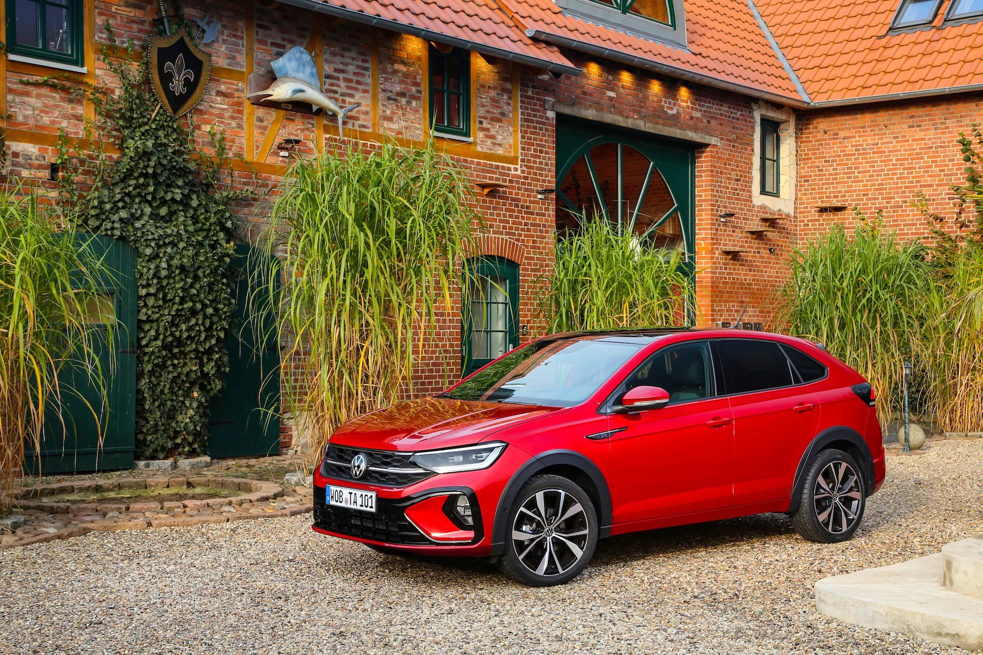 VW Taigo in Rot Seitenansicht parkend vor einem Haus