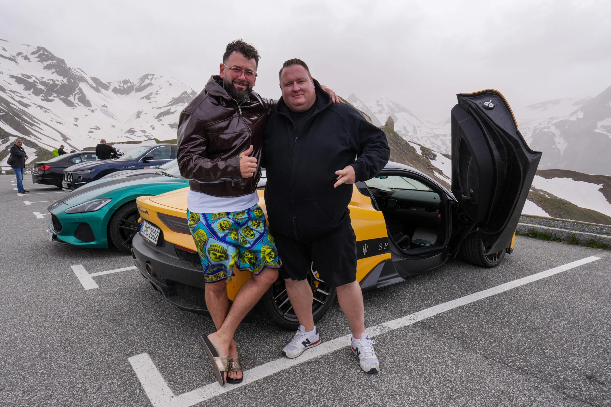 Zwei Teilnehmer vor ihren Fahrzeugen und Alpenpanorama