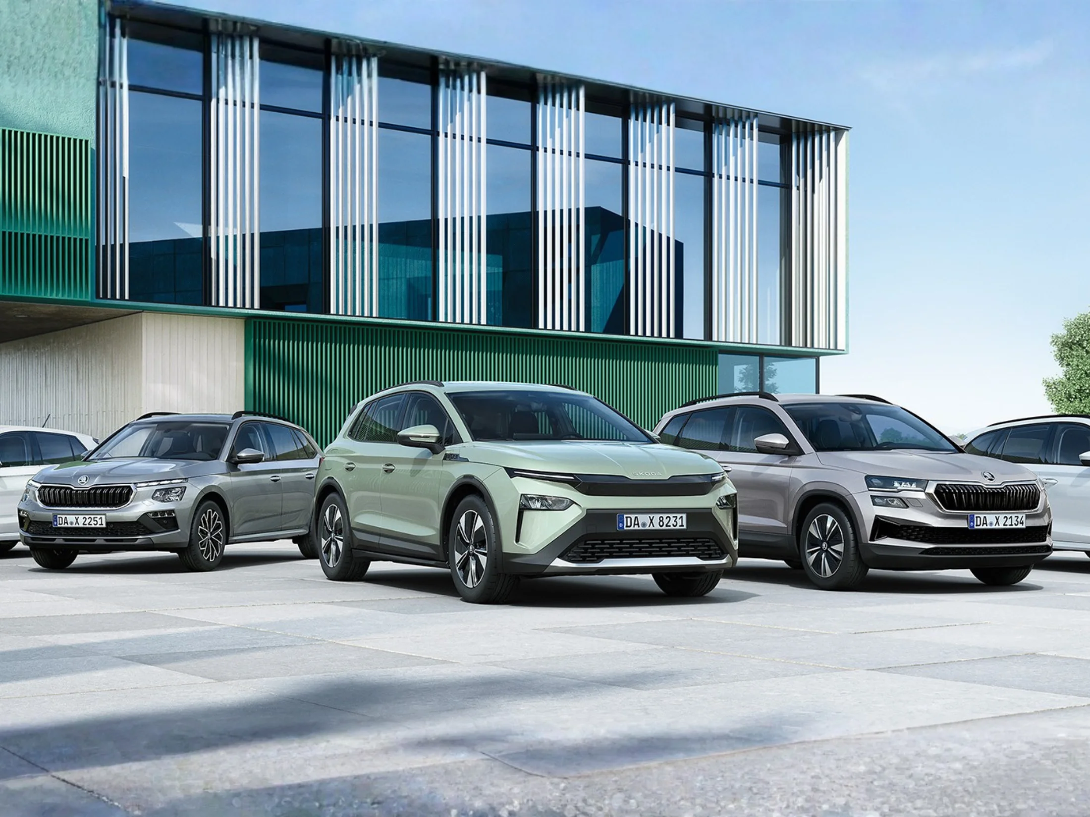 Mehrere Skoda Modelle vor einem modernen Gebäude mit Glasfassade