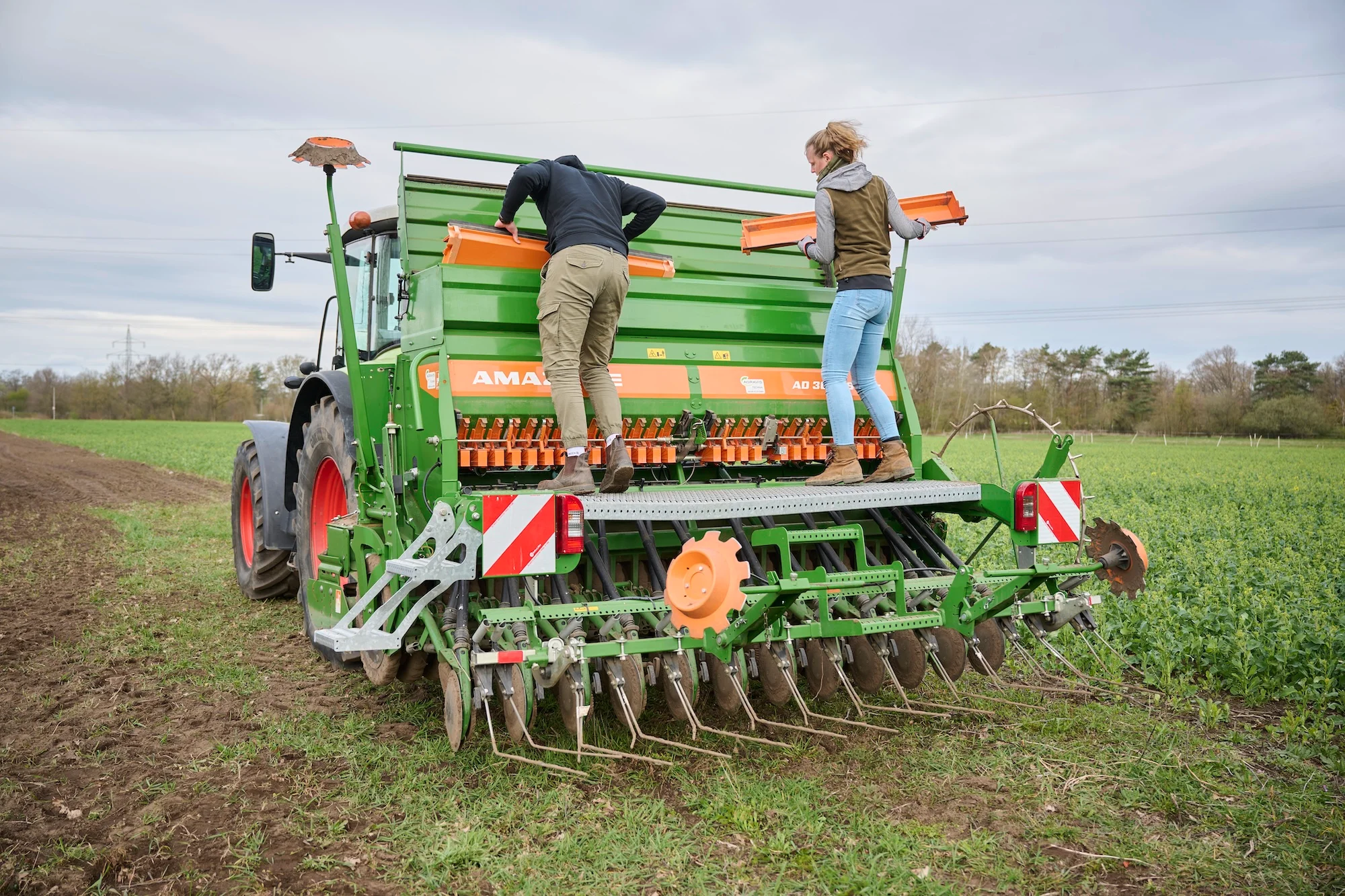 Mitarbeiter von Artenglück, bei der Aussaat von Saatgut auf einer Maschine