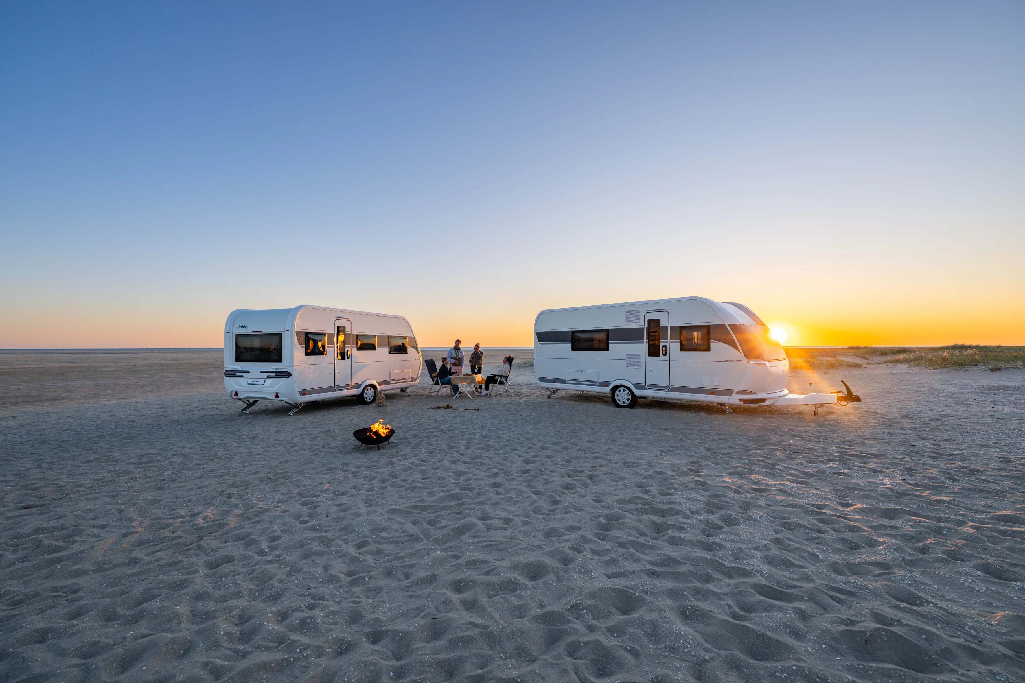 Zwei Hobby Wohnwagen an einem Strand mit Lagerfeuer