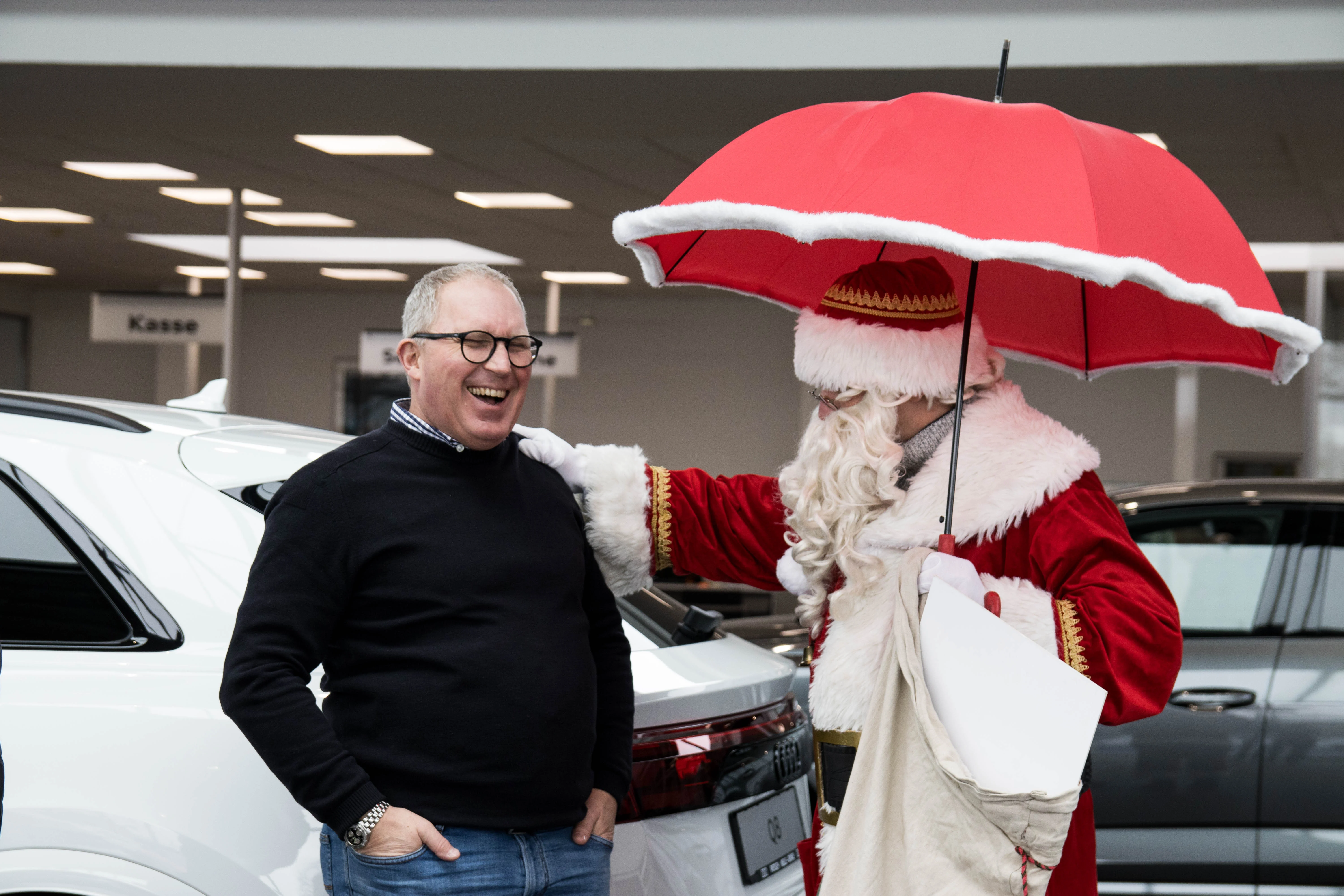 Weihnachtsmann mit Regenschirm bringt Mitarbeiter zum Lachen