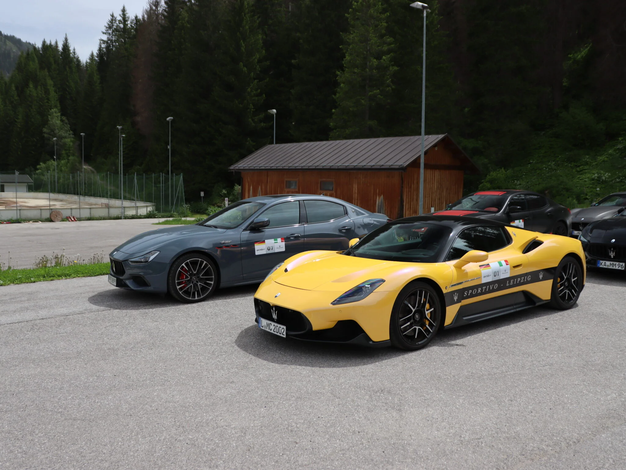 Zwei Maserati in grün und einer gelb auf einem Parkplatz
