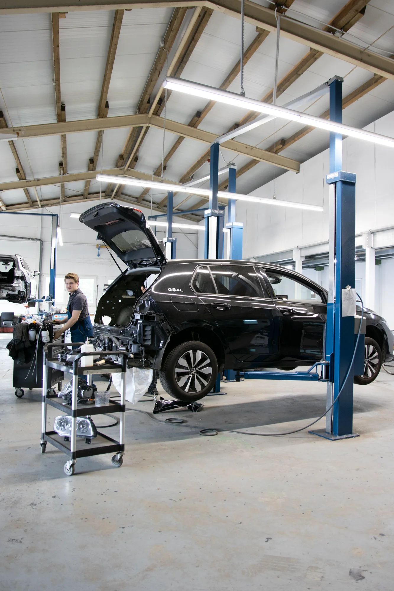 Helle Karosseriewerkstatt mit Auto auf Hebebühne