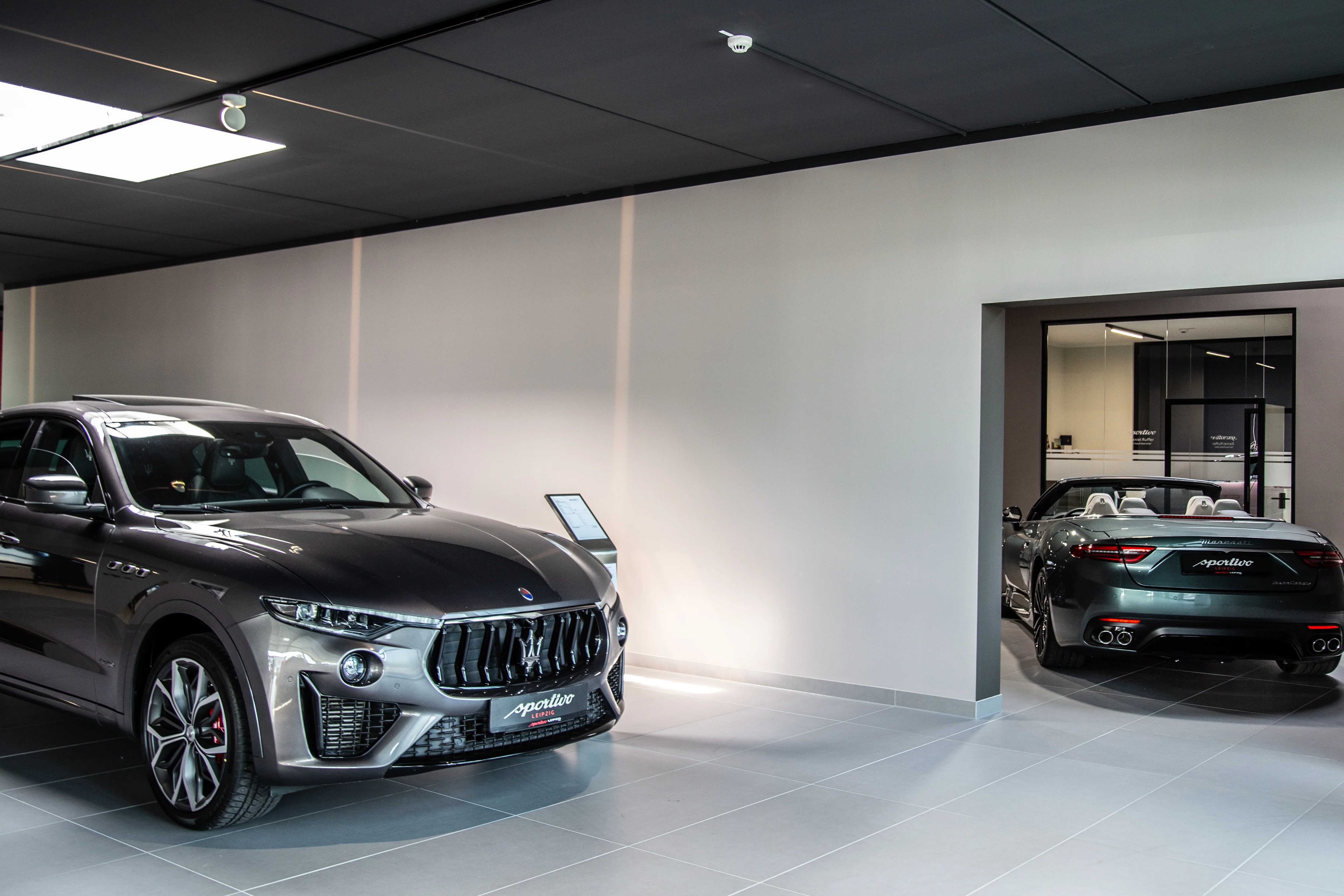 Zwei Maserati Fahrzeuge im Autohaus Sportivo, Sie stehen im rechten Winkel zueinander und sind der eine von vorne und der andere von hinten fotografiert