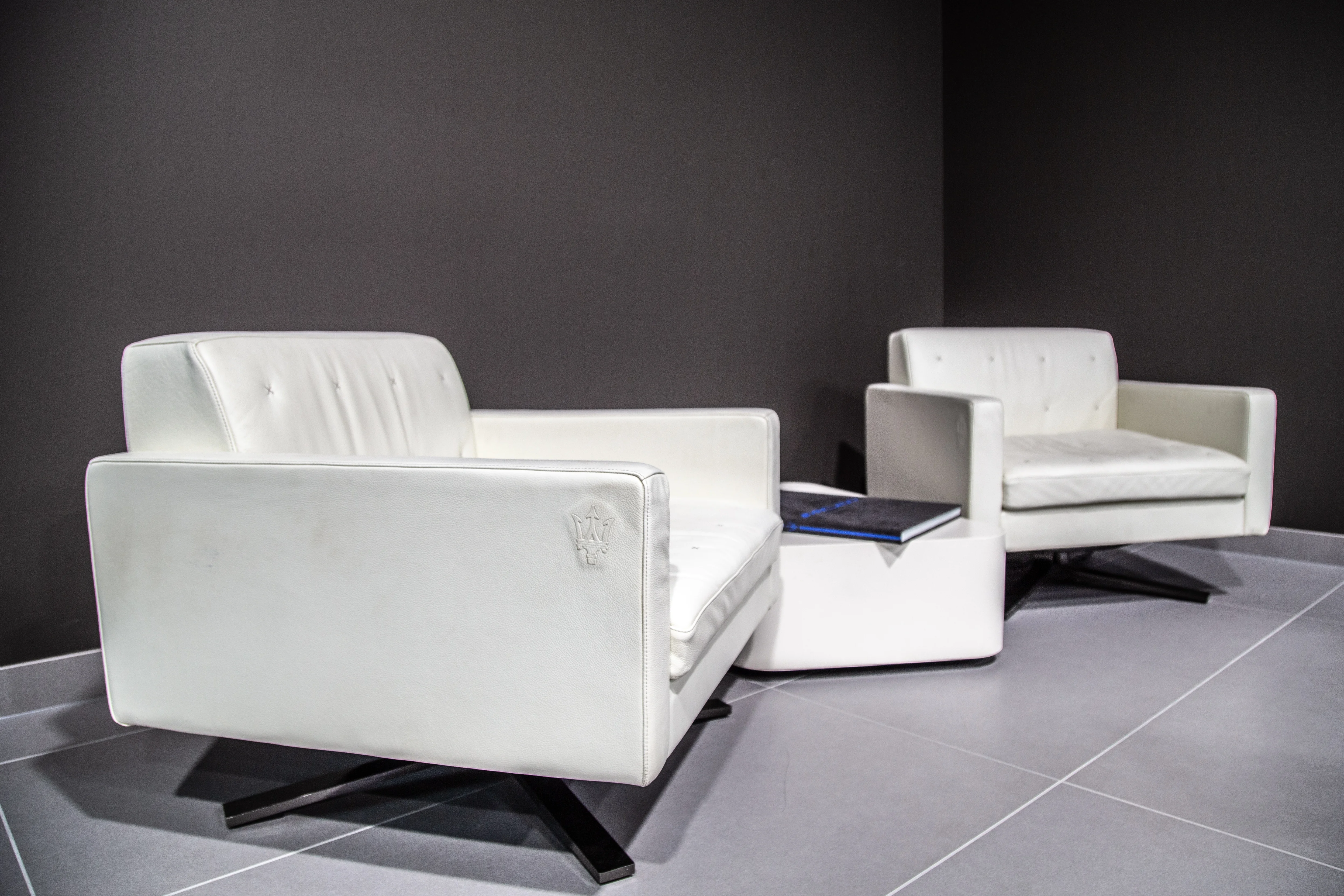 Und deiner Sitzecke im Autohaus Sportivo, mit weißen Leder,sesseln und niedrigen weißen Beistelltisch