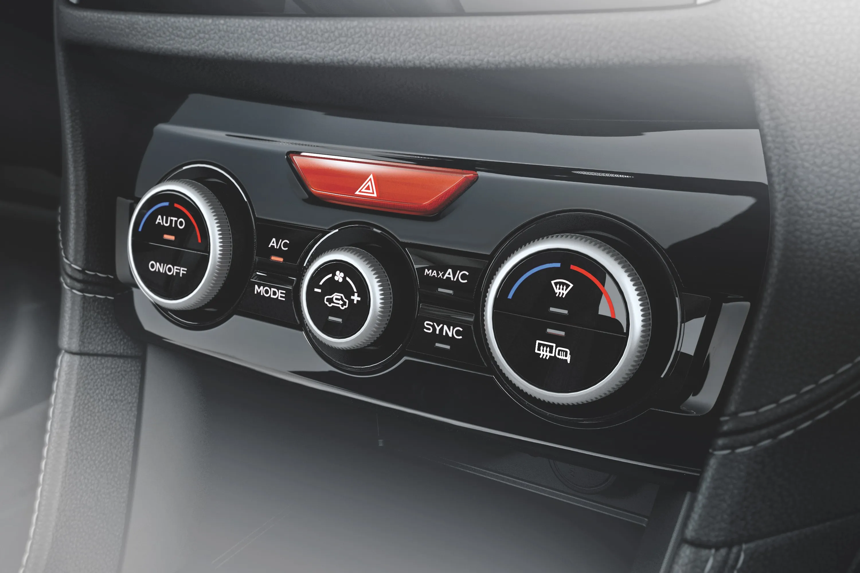 Bedieneinheit für Klimaanlage mit drei Drehreglern und rotem Warnblinkschalter im Auto.