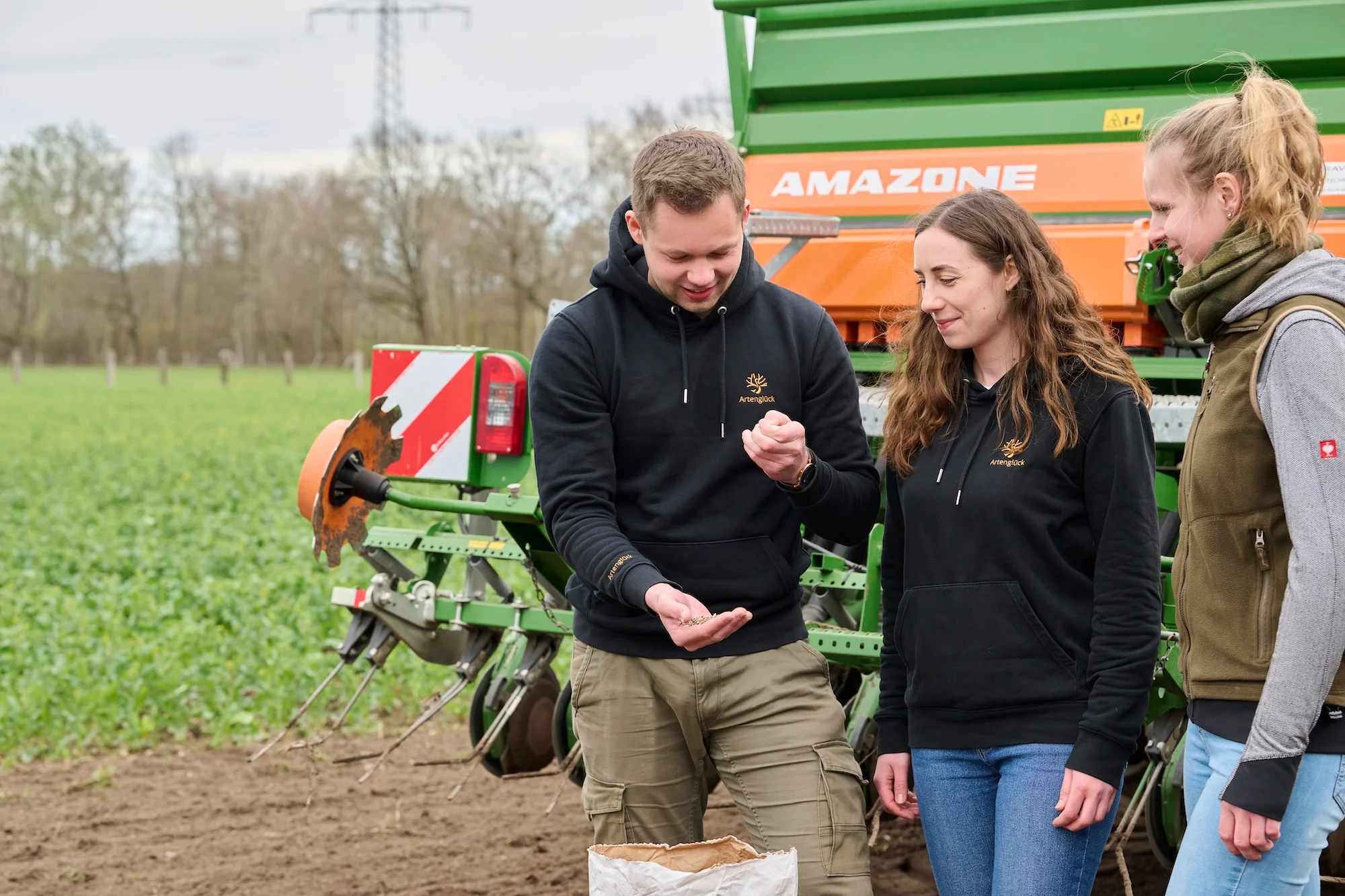 Mitarbeiter von Artenglück, Glück, mit Saatgut hinter einer Saatgut Maschine