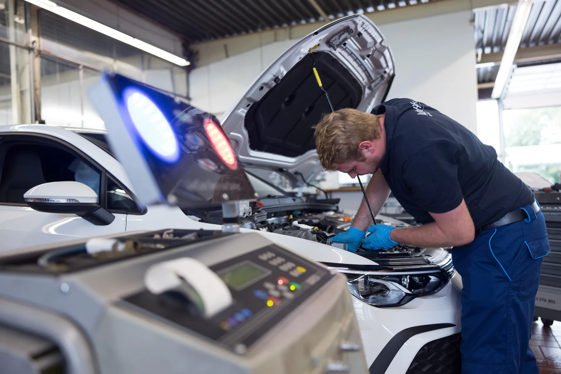 Kfz Mechatroniker mit Tester beim Arbeiten im Autohaus Henke im Motorraum eines PKW
