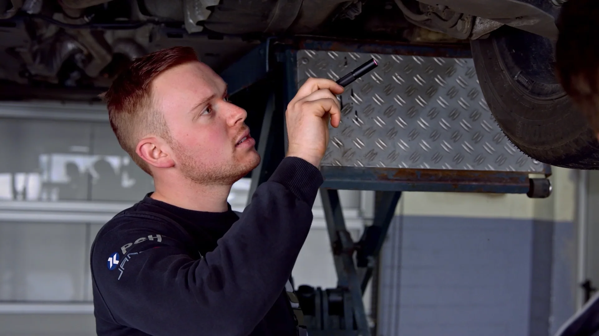 Kfz Mechatroniker bei der Inspektion eines Fahrzeugs hier im Bereich Fahrzeugachse