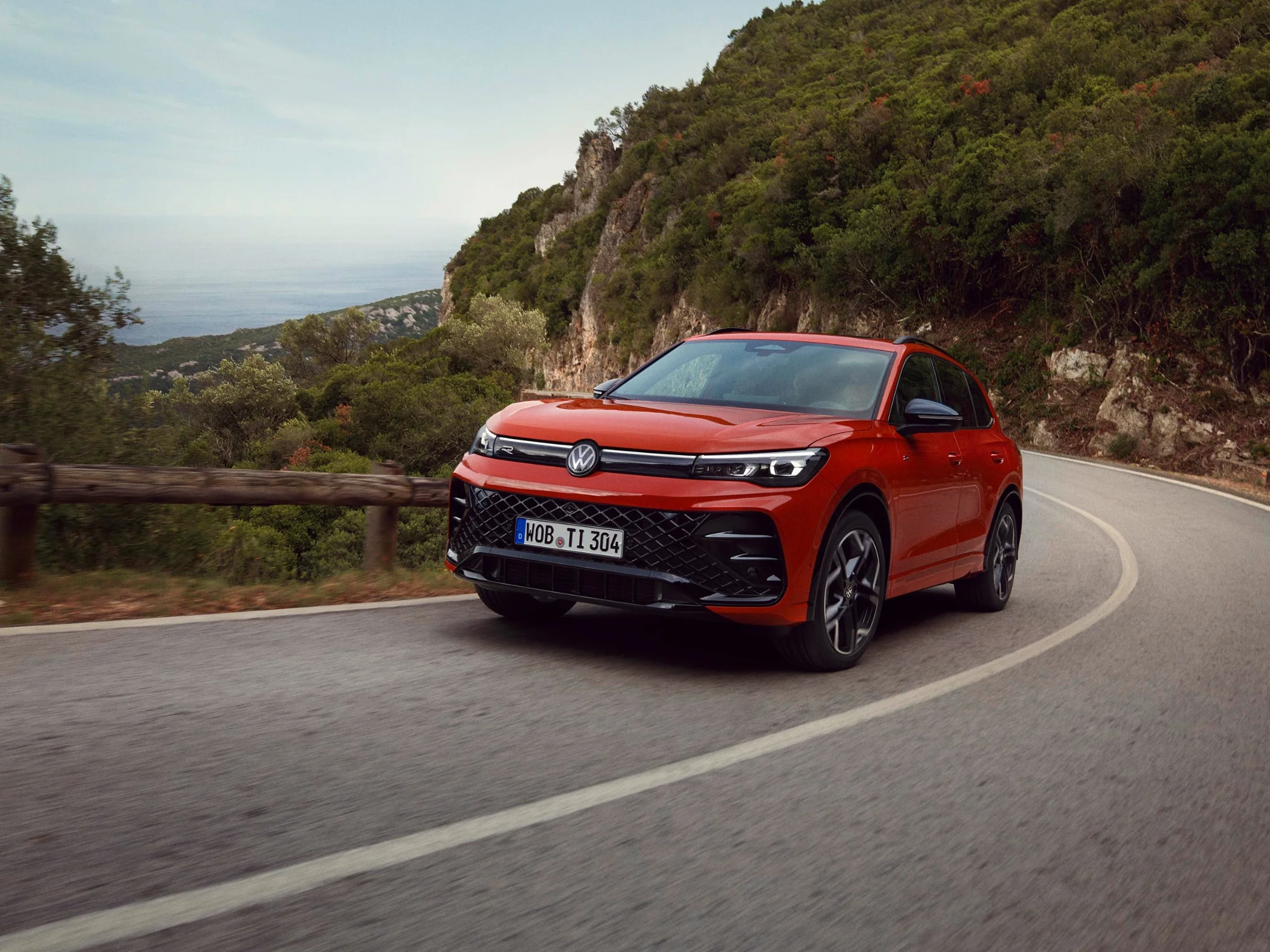 Roter Tiguan fahrend auf Bergstraße.png