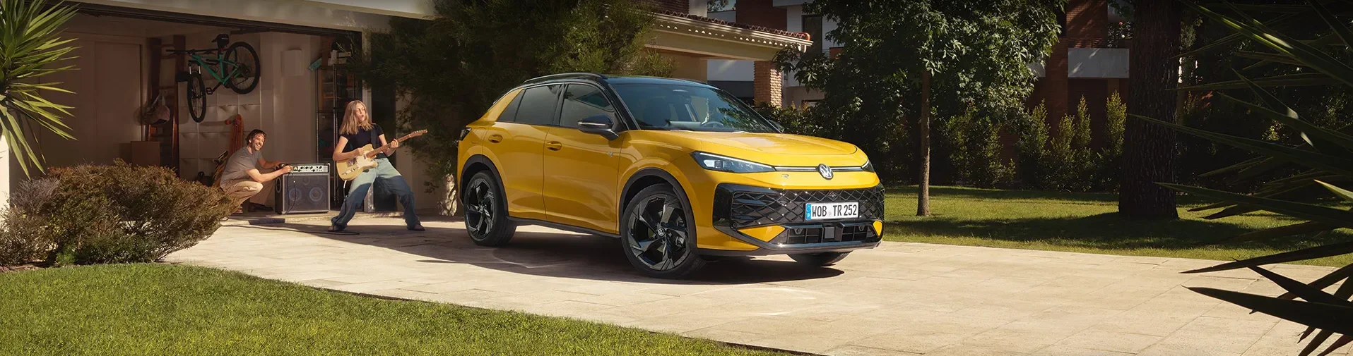 T-Roc in gelb auf einer Garageneinfahrt vor einem modernem Haus