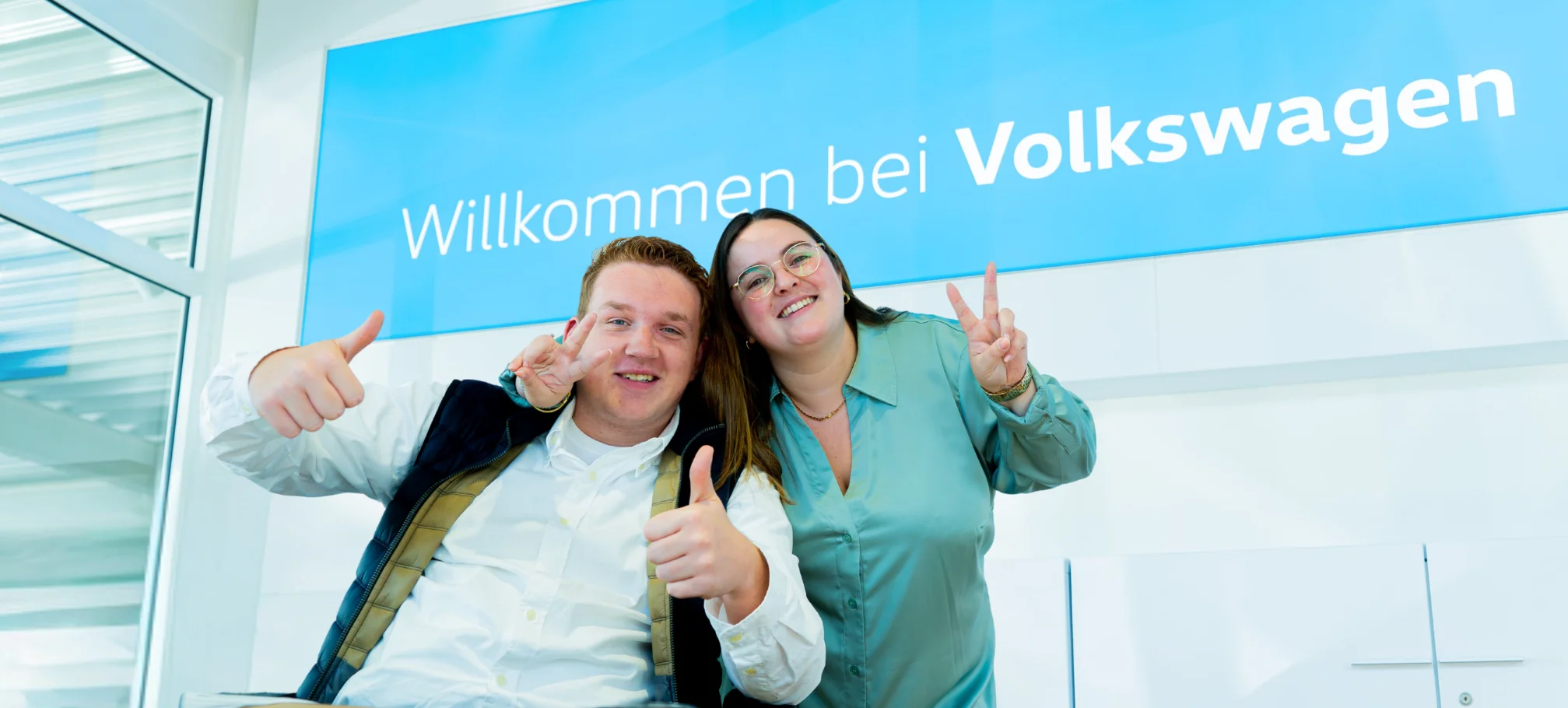 Mitarbeiter des Autohaus Pietsch, freudig aufgeregt vor einem Volkswagen Banner